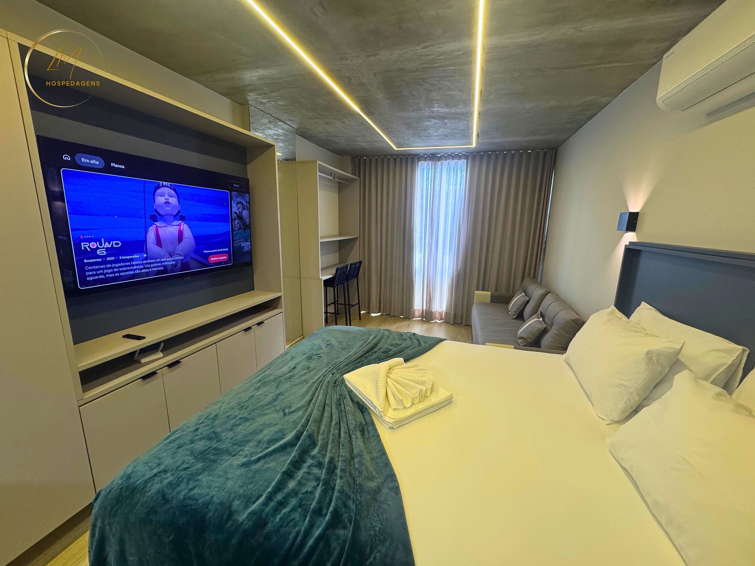 A hotel room with a bed, a TV, a desk, and a seating area.