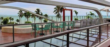 A deck with glass railings, outdoor seating, and a view of the ocean.