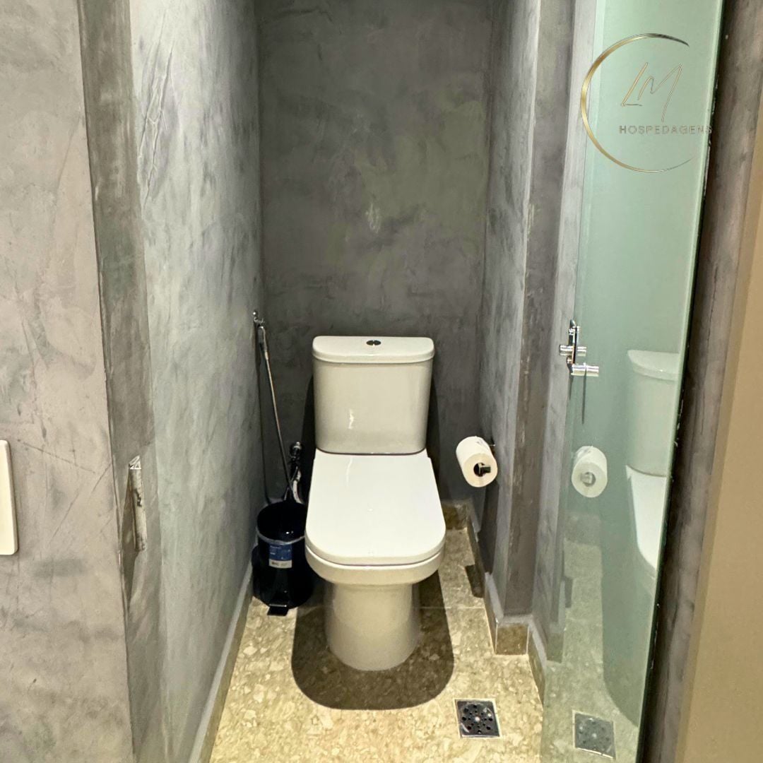 A small, narrow bathroom with a toilet, bidet, and a mop.