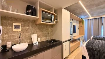 Una habitación de hotel moderna con cocina, cama y televisor.