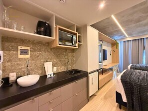 Una habitación de hotel moderna con cocina, cama y televisor.