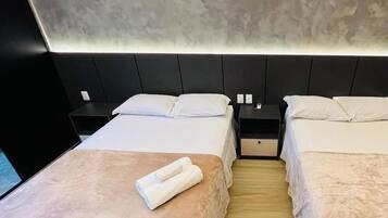 Una camera d'albergo con due letti, un comodino, un condizionatore d'aria e un pavimento in legno.