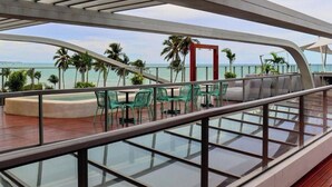 Une terrasse dotée de rampes en verre, d’un espace salon extérieur et offrant une vue sur l’océan.