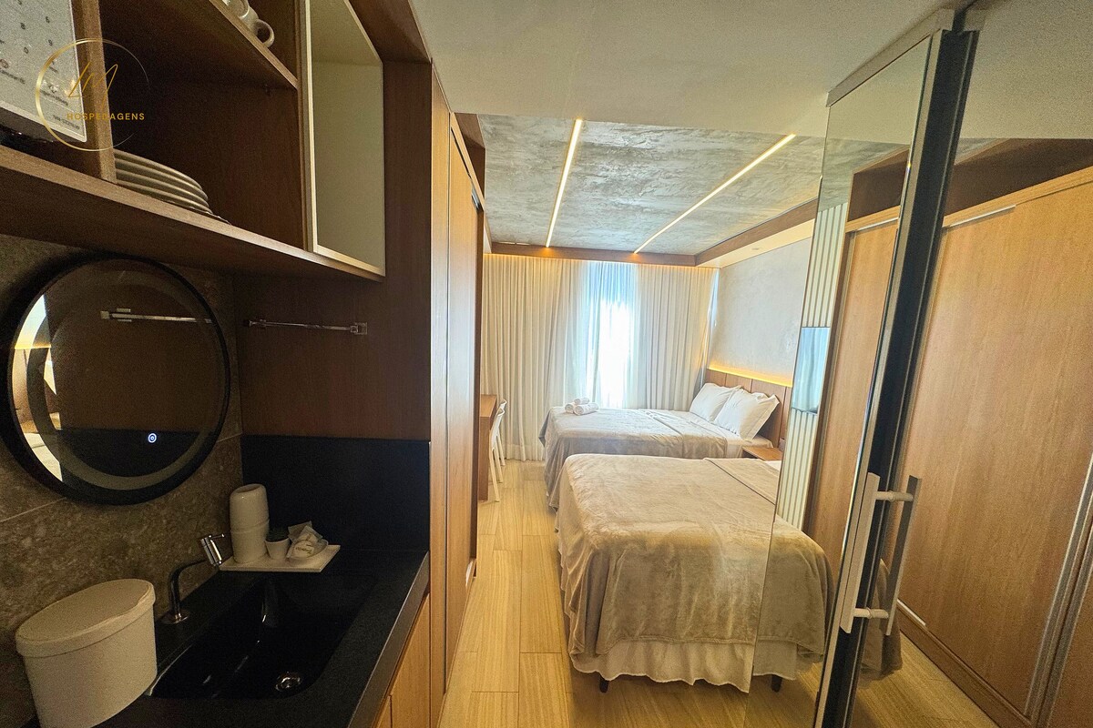 Una habitación de hotel con baño, cama, espejo y armario.