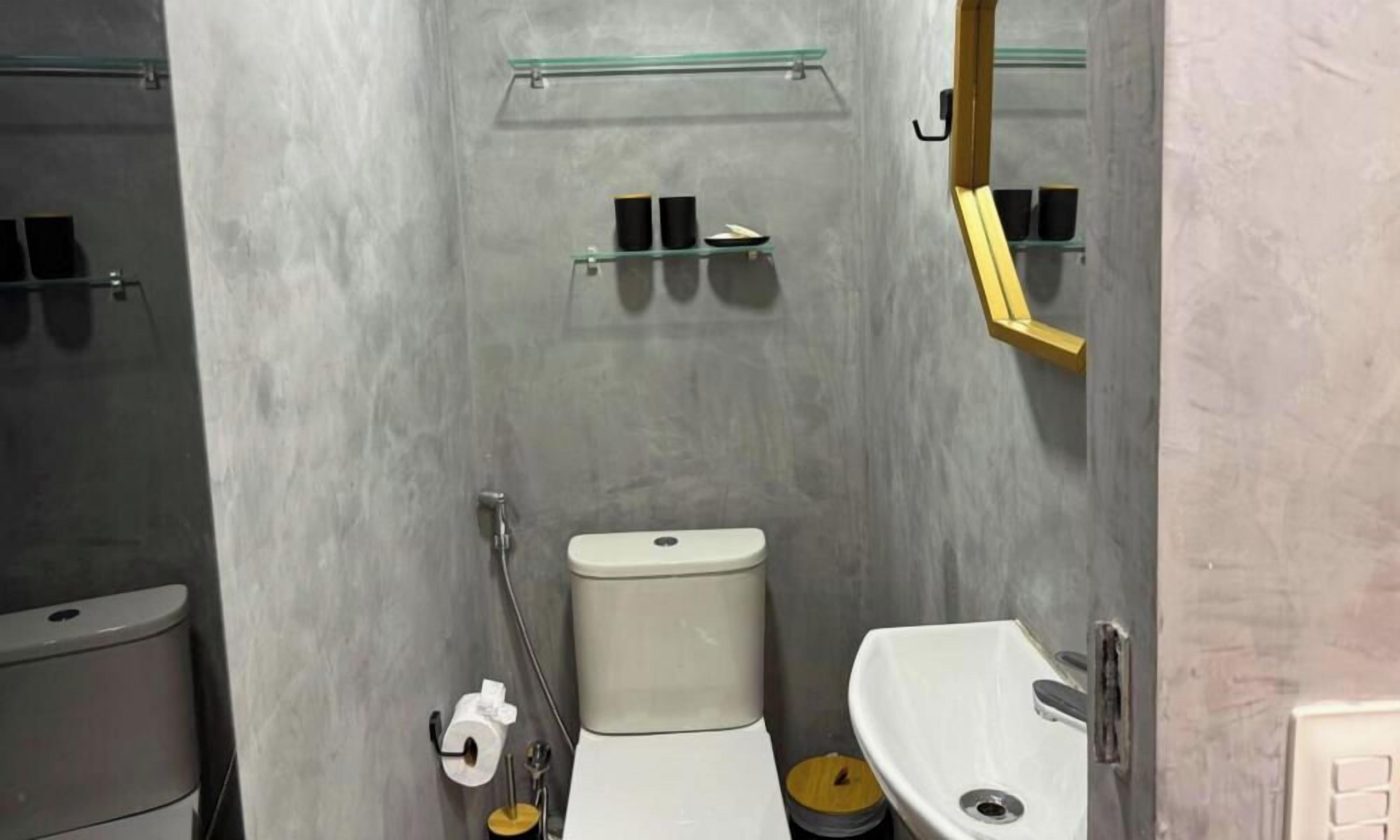 Un baño con inodoro, lavabo y estantes de vidrio.