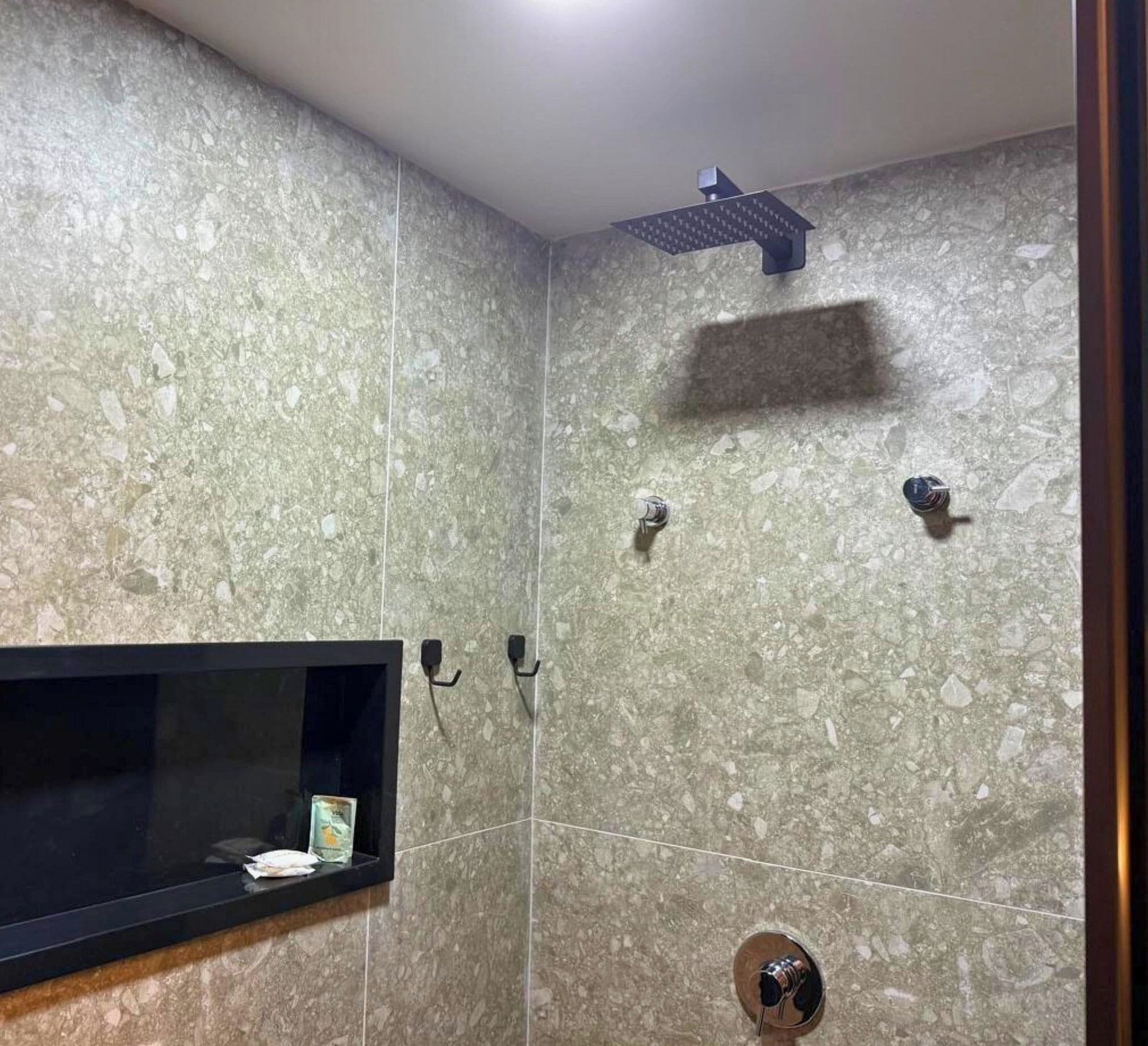 Ein Badezimmer mit Dusche, einem Regal mit einem Buch und einem Handtuchhalter.