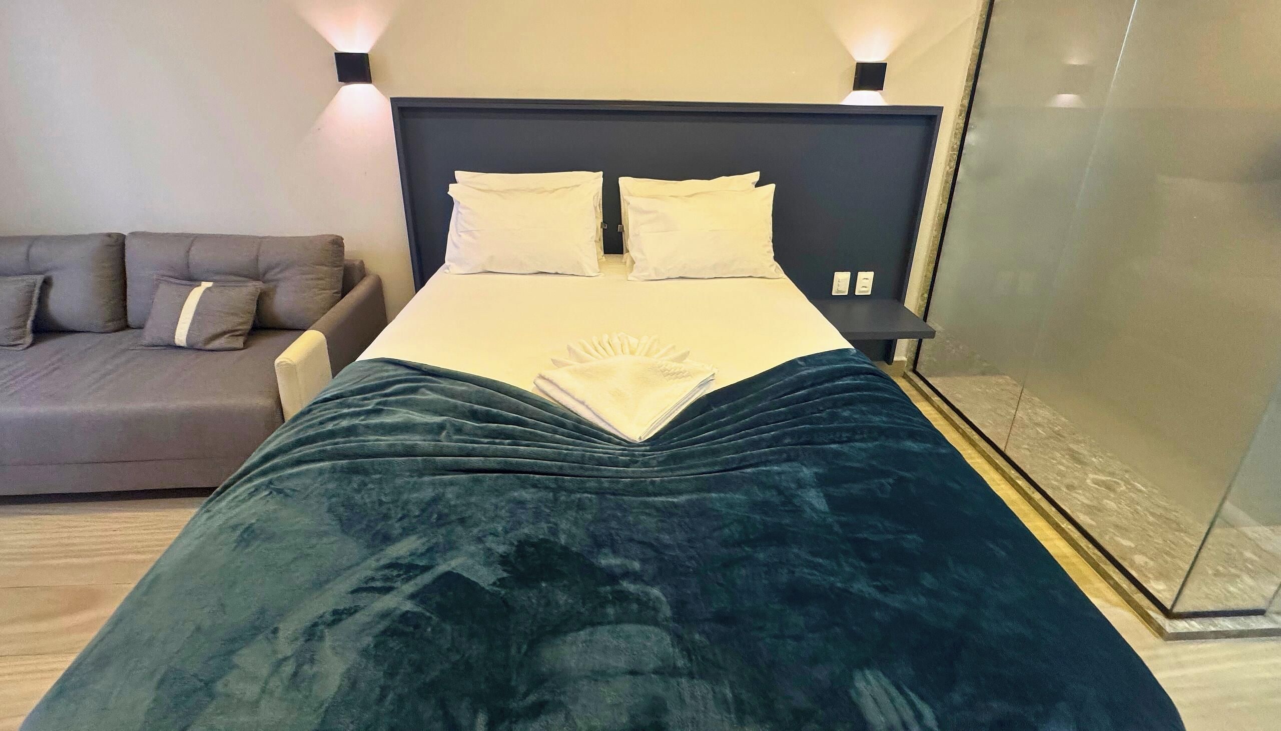 A bed with a dark blue blanket, a white pillow, and a white duvet.