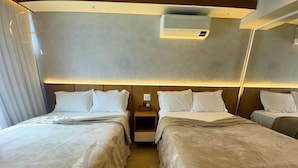 Une chambre d’hôtel avec deux lits, une table de chevet, un appareil de climatisation et un miroir au mur.