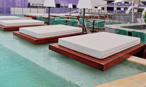 Un área de piscina en la azotea con varias sillas de descanso y algunas mesas.