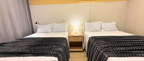 Une chambre d’hôtel avec deux lits, une table de chevet avec une lampe et un appareil de climatisation fixé au mur.