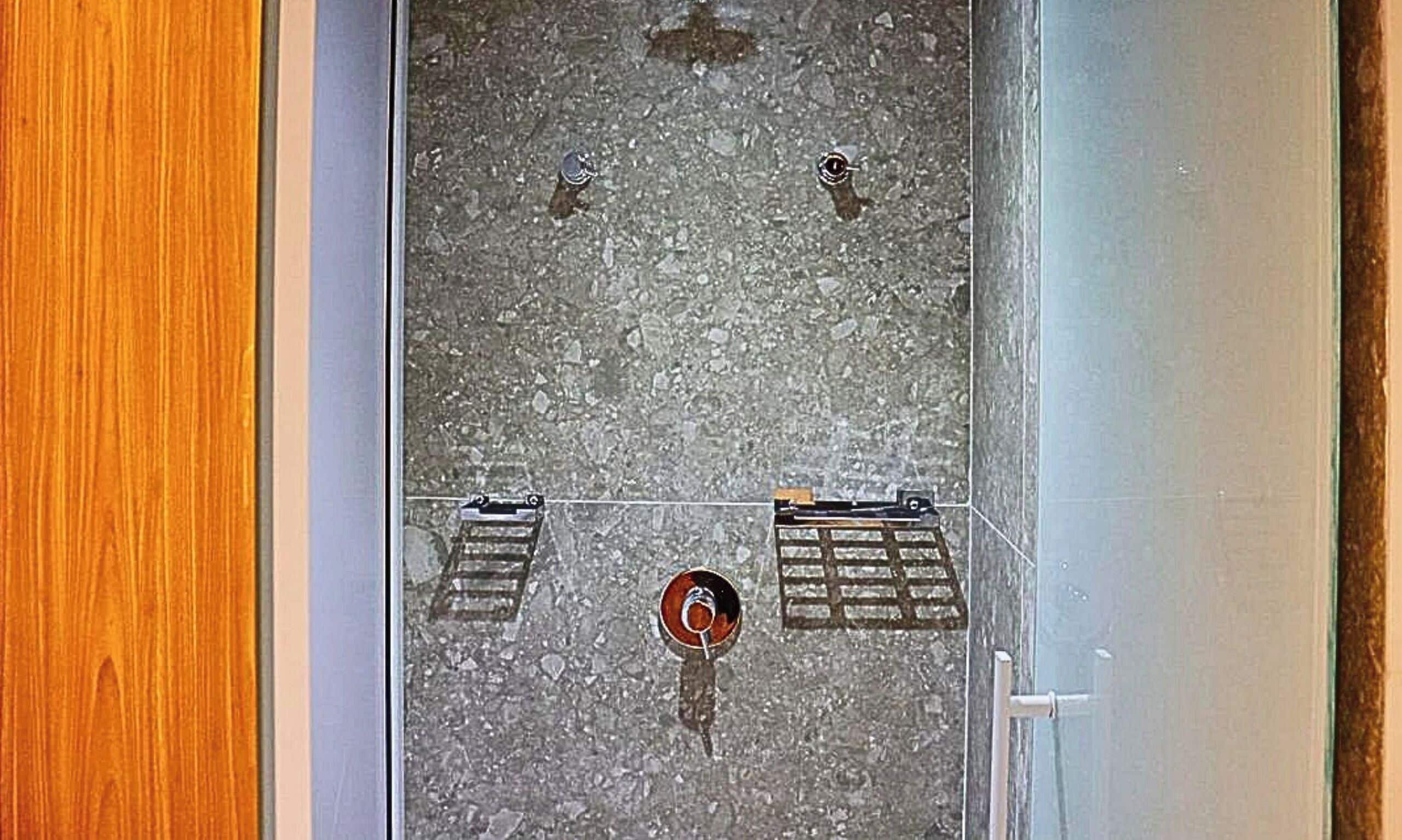 A tiled floor with two metal grates and a circular drain.