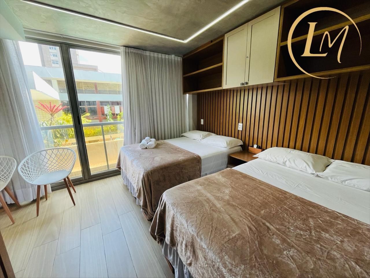 A hotel room with two beds, a small table, and a chair.