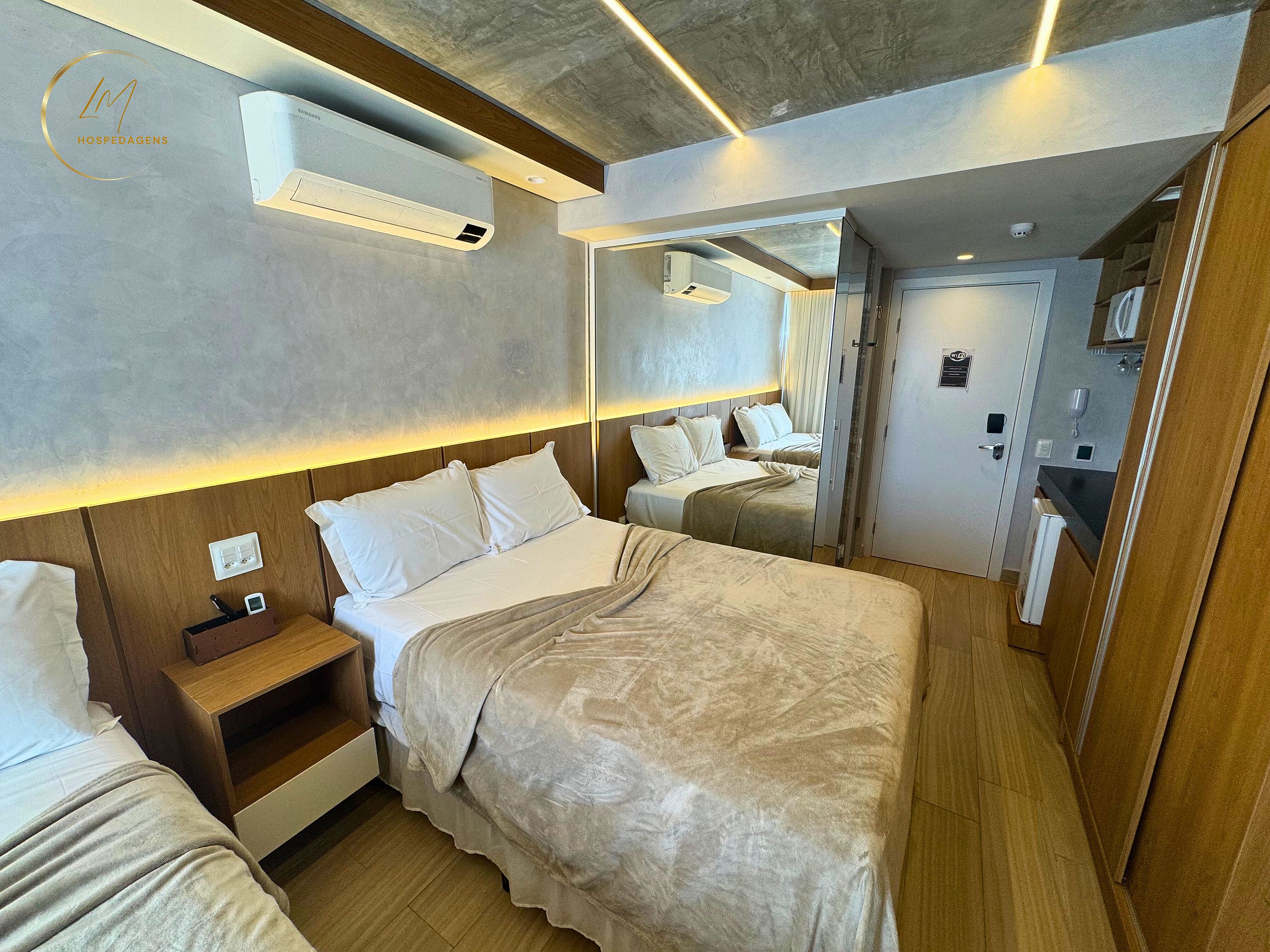 Une chambre d’hôtel moderne avec un grand lit, des tables de chevet, un miroir et un appareil de climatisation.