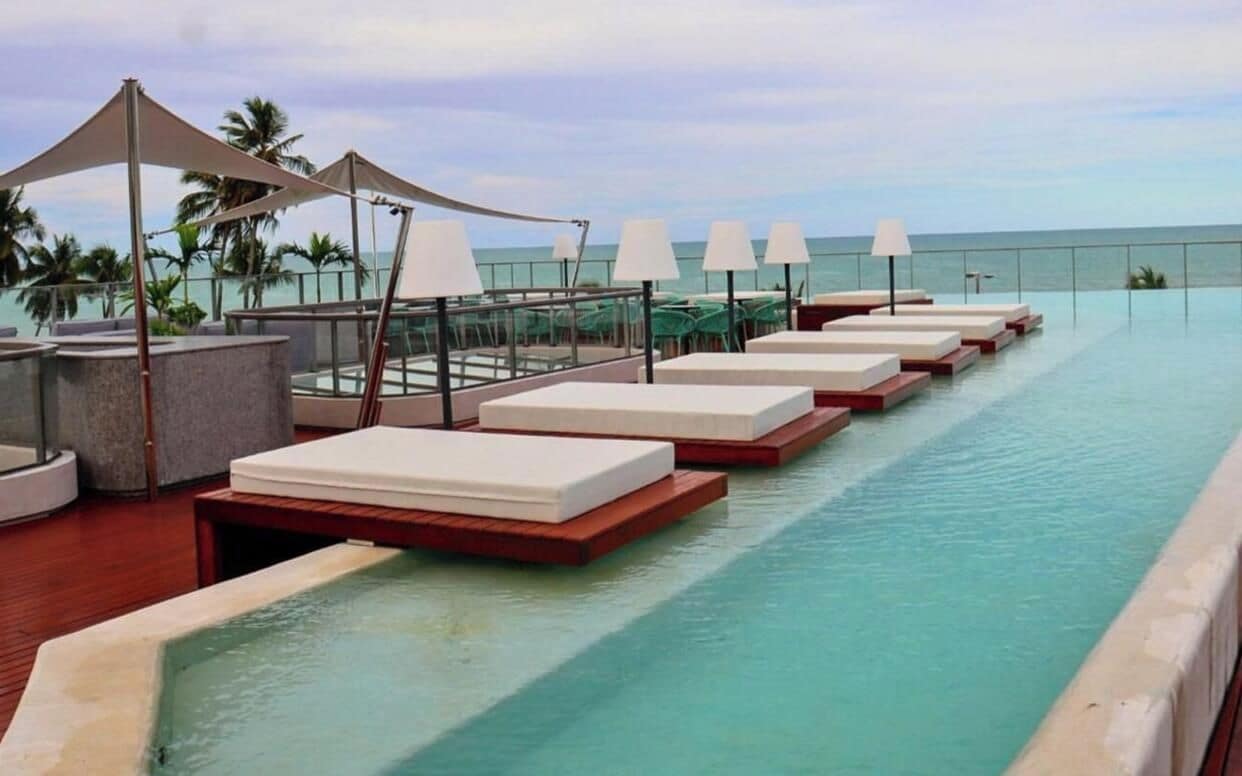 Ein Poolbereich mit Liegestühlen und Sonnenschirmen mit Blick auf das Meer.