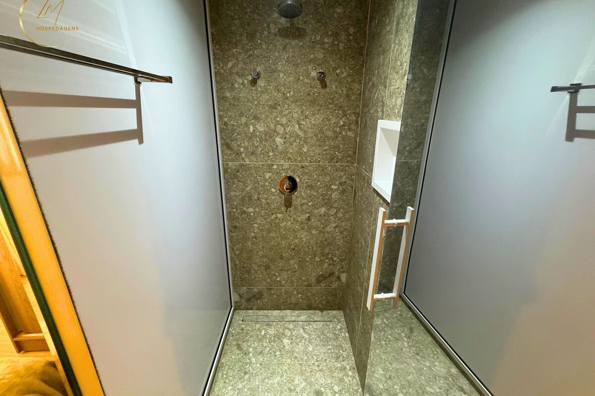 A narrow, tiled shower area with a showerhead and a towel rack.