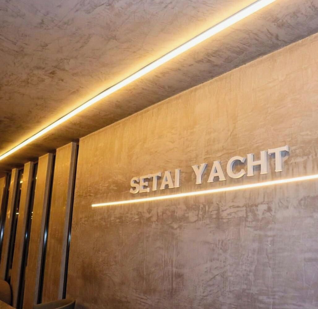 A wall with the text 'SETAI YACHT' illuminated by underglow lighting.