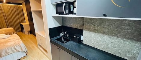 A compact kitchenette with a microwave, sink, and storage cabinets.