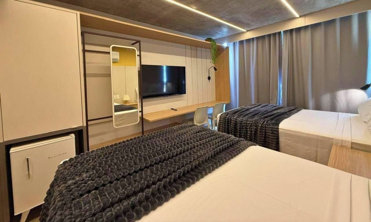 Une chambre d’hôtel moderne équipée d’un grand lit, d’un bureau, d’une télévision et d’une armoire.