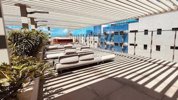 A modern outdoor seating area with a curved ceiling and a view of a building in the background.