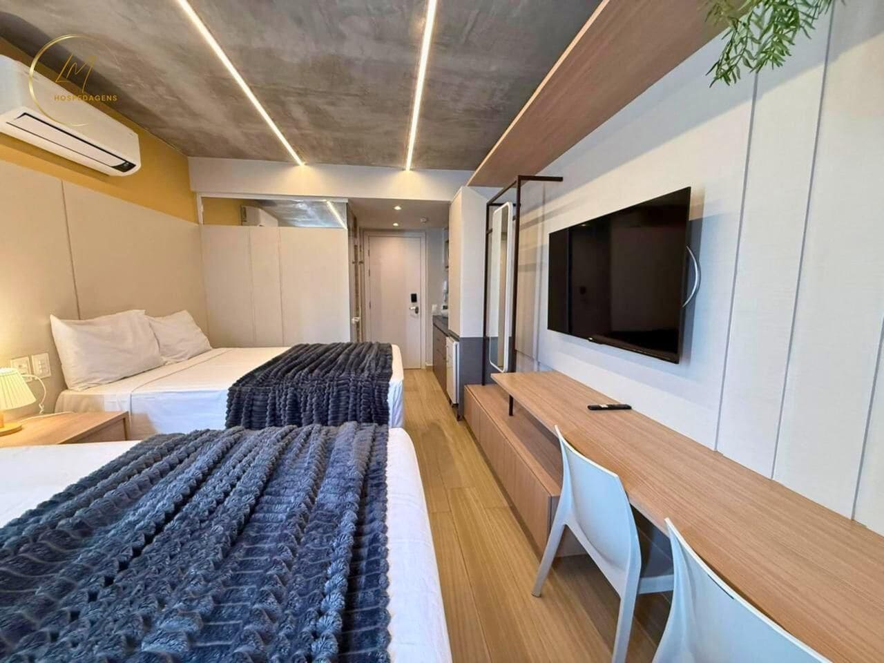 Une chambre d’hôtel moderne équipée de deux lits, d’un bureau, d’une télévision et d’un appareil de climatisation.