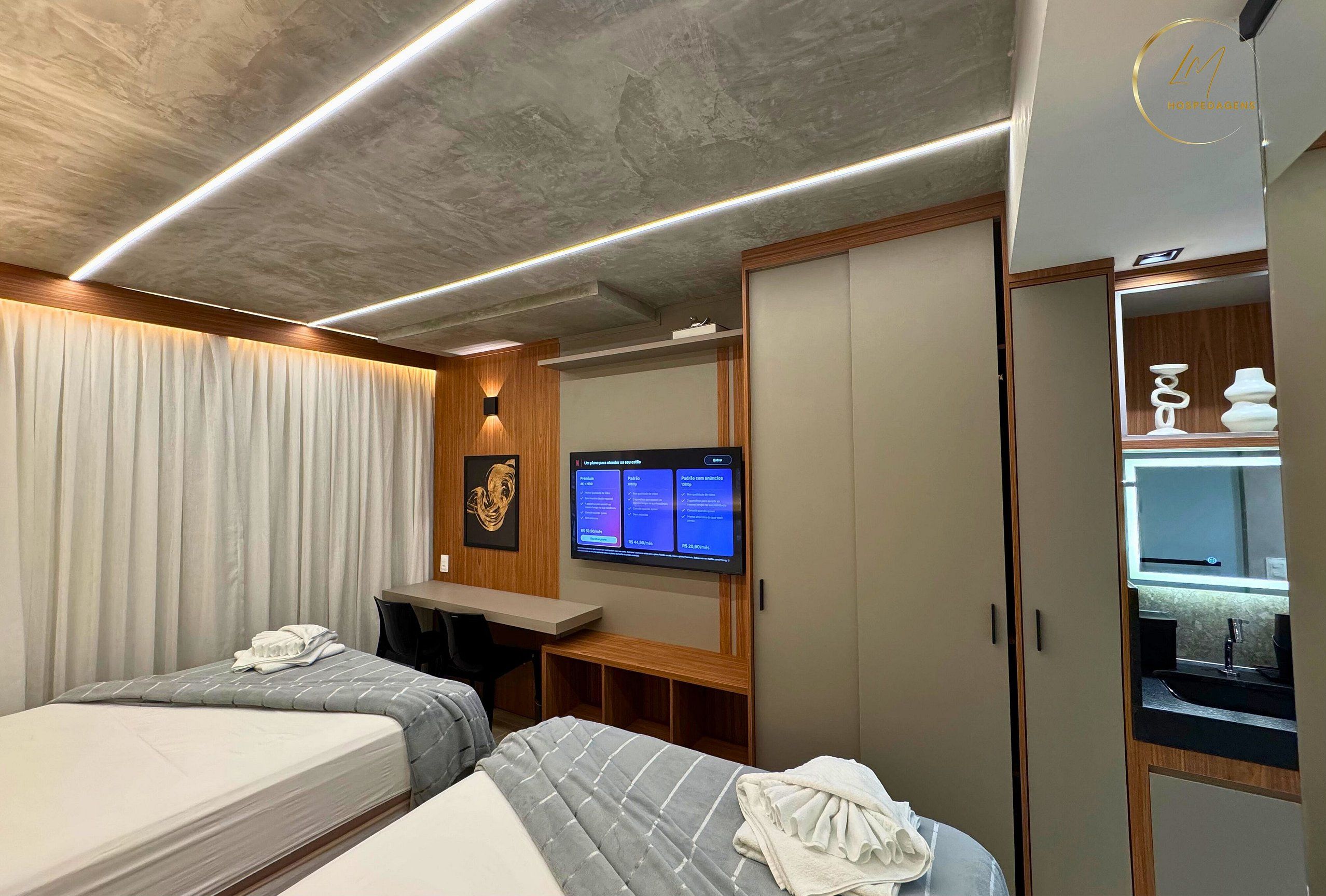 Habitación de hotel con dos camas, un escritorio, televisor y armario.