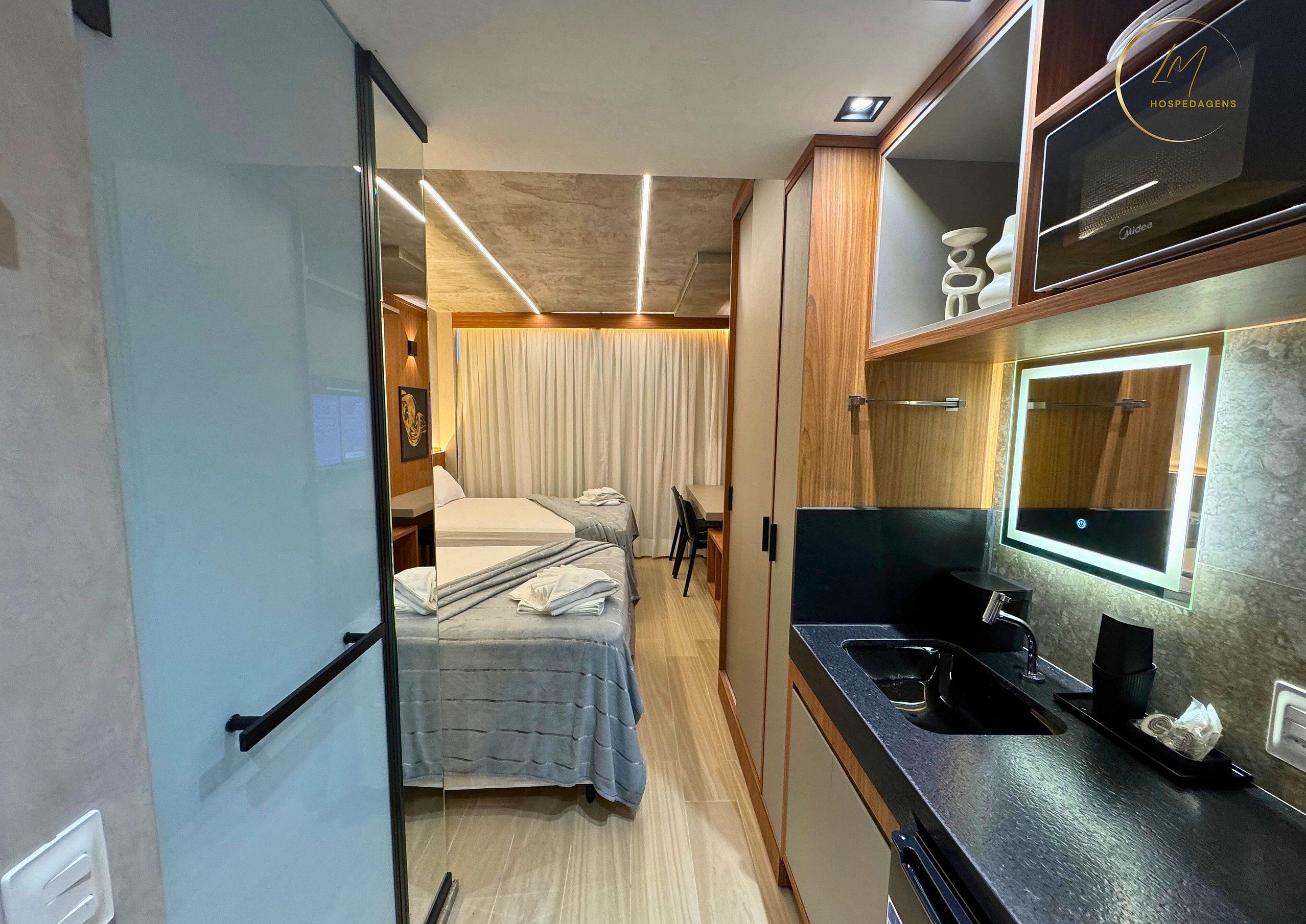 Habitació d'hotel compacta amb llit, taula de nit i mirall integrat sobre el rentapans.