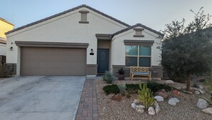 A single-story house with a garage, a front door, and a small porch with a bench. - Blue Door Retreat - 
a home in Tartesso, Buckeye, AZ (Buckeye)