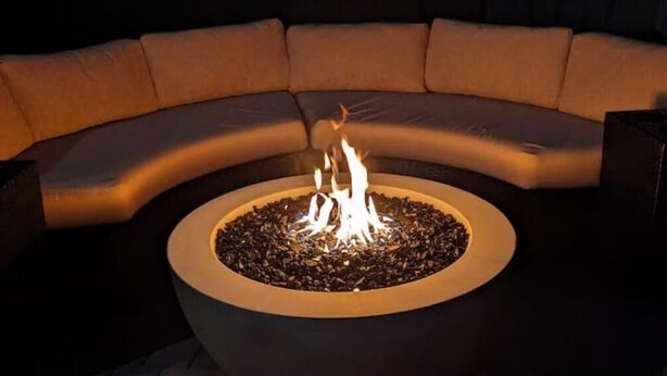 A circular fire pit with flames in the center, surrounded by a curved seating area. - Blue Door Retreat - 
a home in Tartesso, Buckeye, AZ (Buckeye)