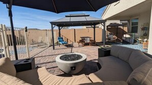 An outdoor patio with a fire pit, lounge chairs, and a covered seating area. - Blue Door Retreat - 
a home in Tartesso, Buckeye, AZ (Buckeye)