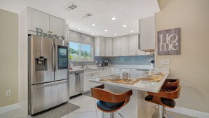 A modern kitchen with stainless steel appliances, a dining area with wooden chairs, and a view of the outdoors. - Charming 3-bedroom house with private pool  and in delightful Sarasota...  (Sarasota)