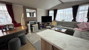 A modern living room with a sofa, a TV, a fireplace, and a dining area with a table and chairs.