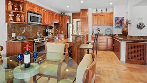 A modern kitchen with wooden cabinets, a glass dining table, and a central island. - 2 bedroom condo, marina view in Terrasol Beach Resort, 15 min walk to everything (Cabo San Lucas)