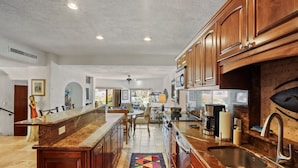 A spacious kitchen with wooden cabinets, a marble countertop, and a colorful rug. - 2 bedroom condo, marina view in Terrasol Beach Resort, 15 min walk to everything (Cabo San Lucas)