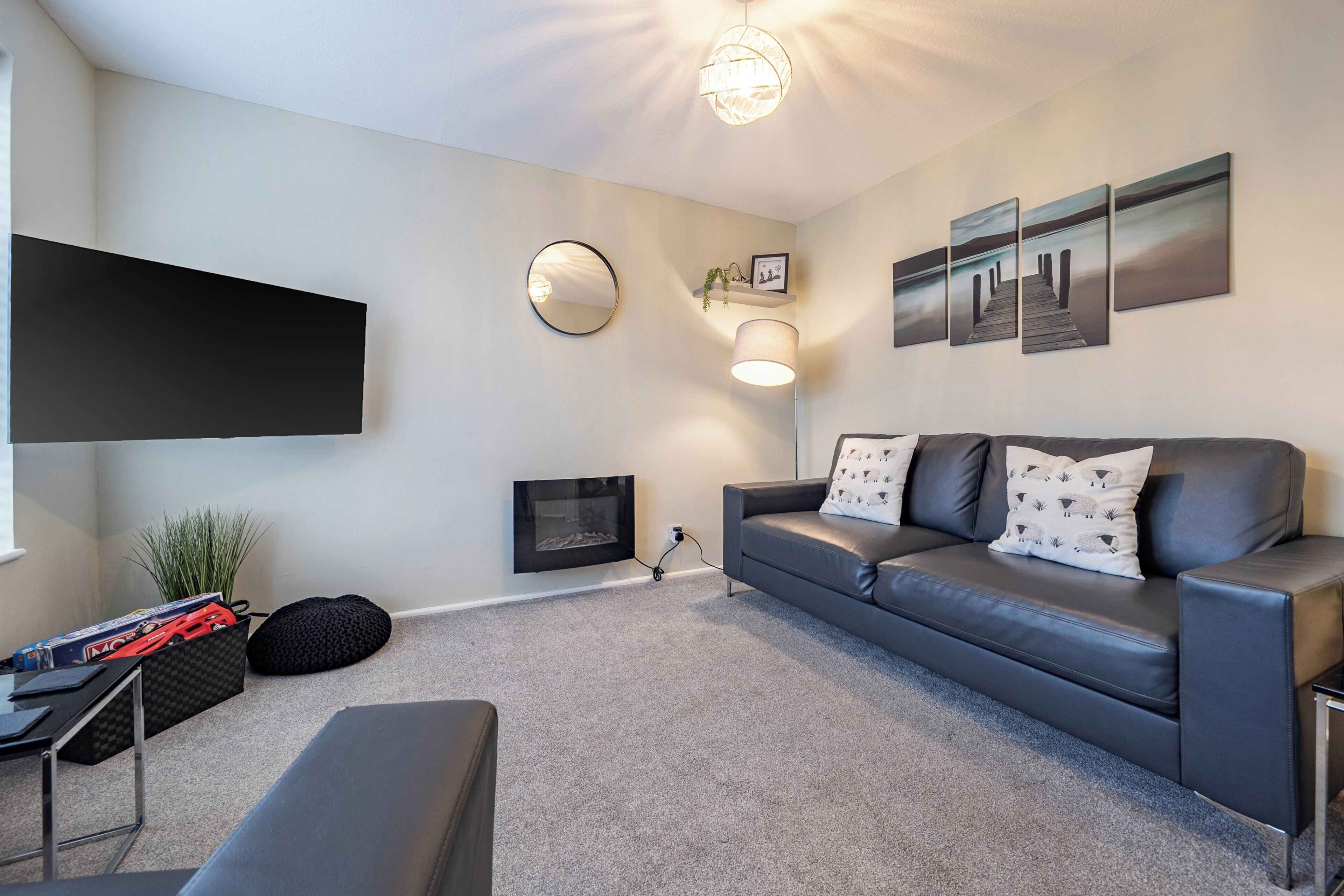 A modern living room with a sofa, a flat-screen TV, a fireplace, and artwork on the wall.