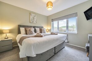 A bedroom with a bed, bedside lamps, a window, and a flat-screen TV. - 2 Bed House - Sleeps 4 - Garden - Parking - Wifi (Kendal)
