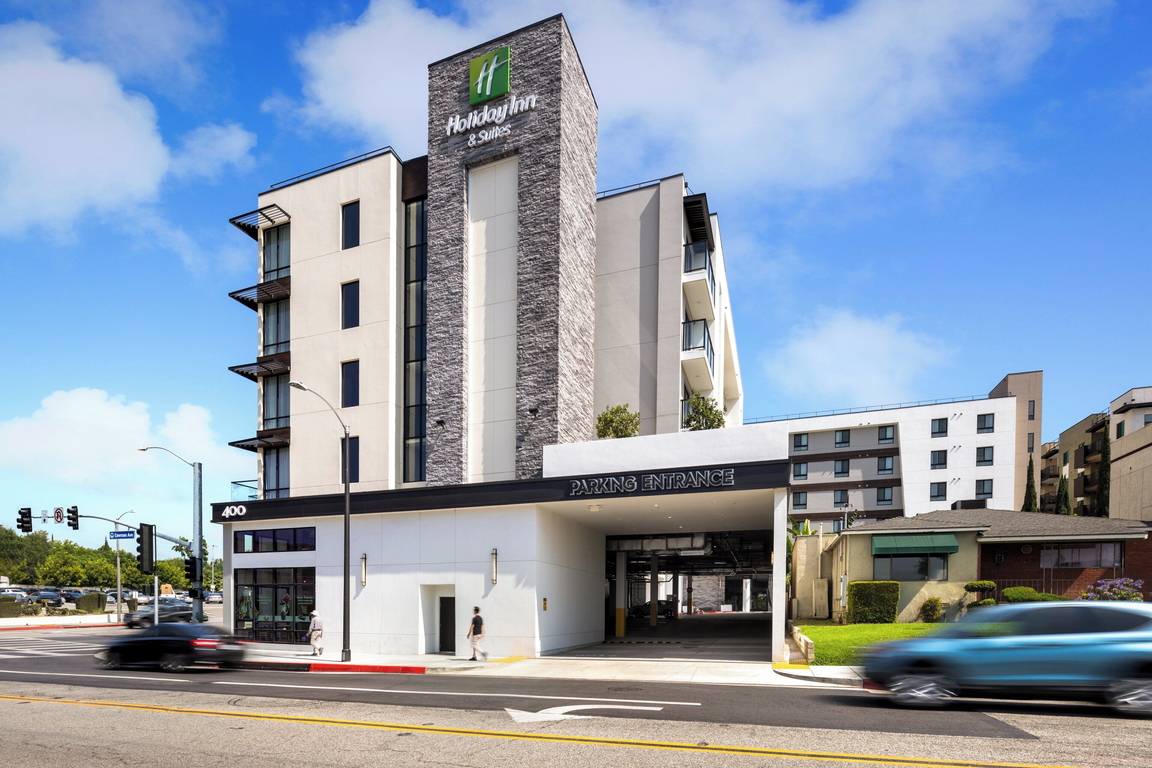 A Holiday Inn & Suites building with a parking entrance, multiple floors, and a modern architectural design.