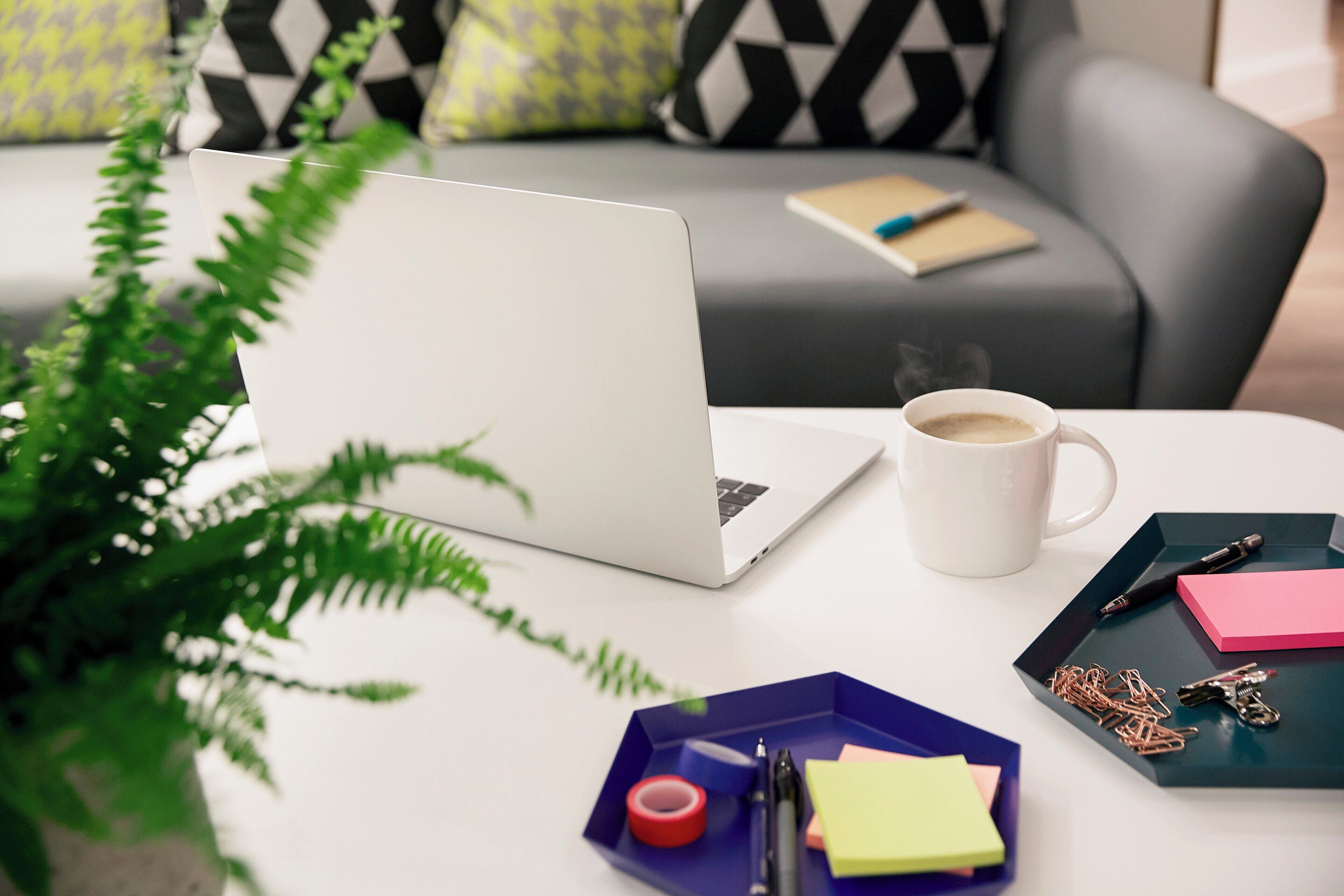 A laptop on a table with a cup of coffee, sticky notes, and keys.