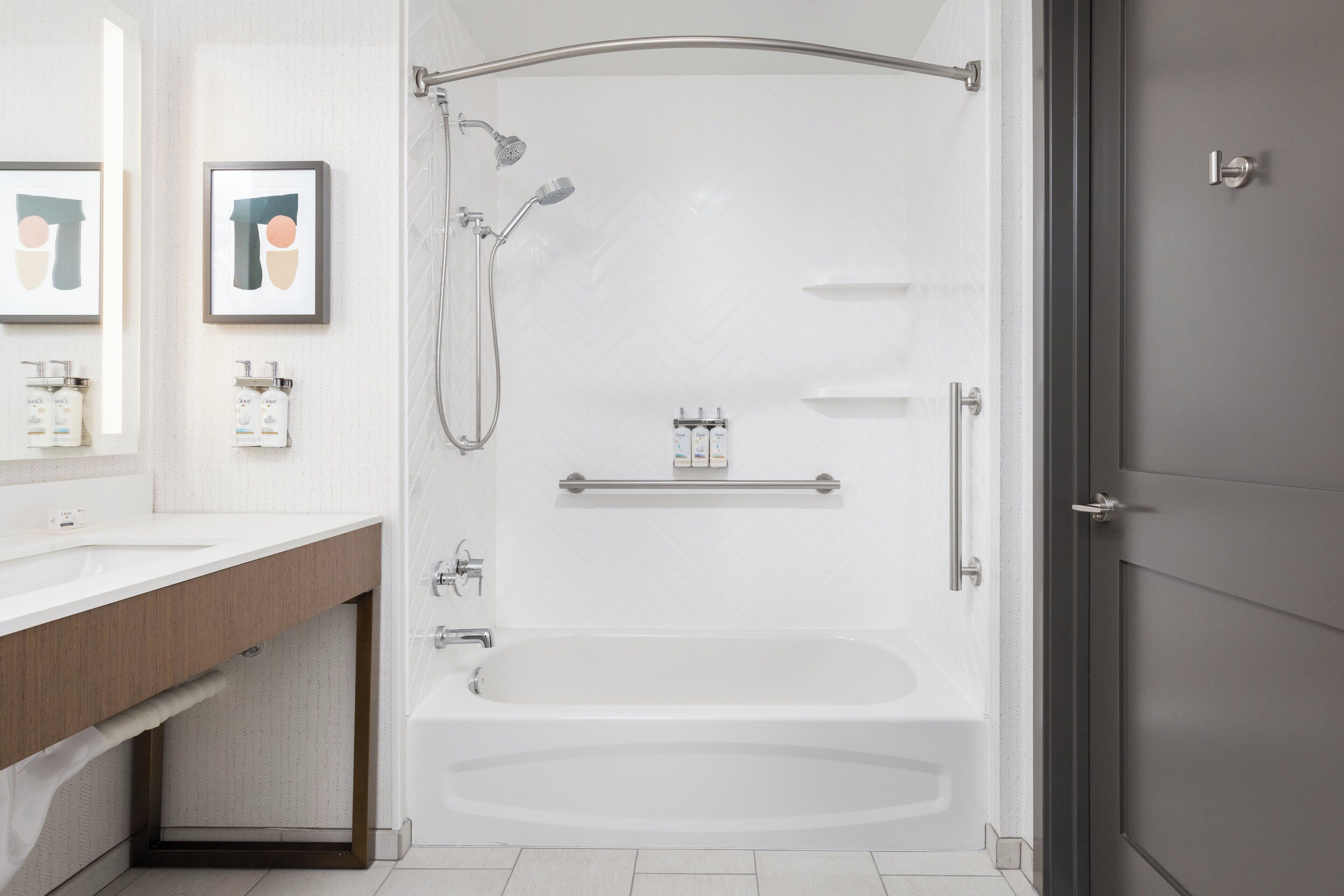 A modern bathroom with a bathtub, shower, and vanity.