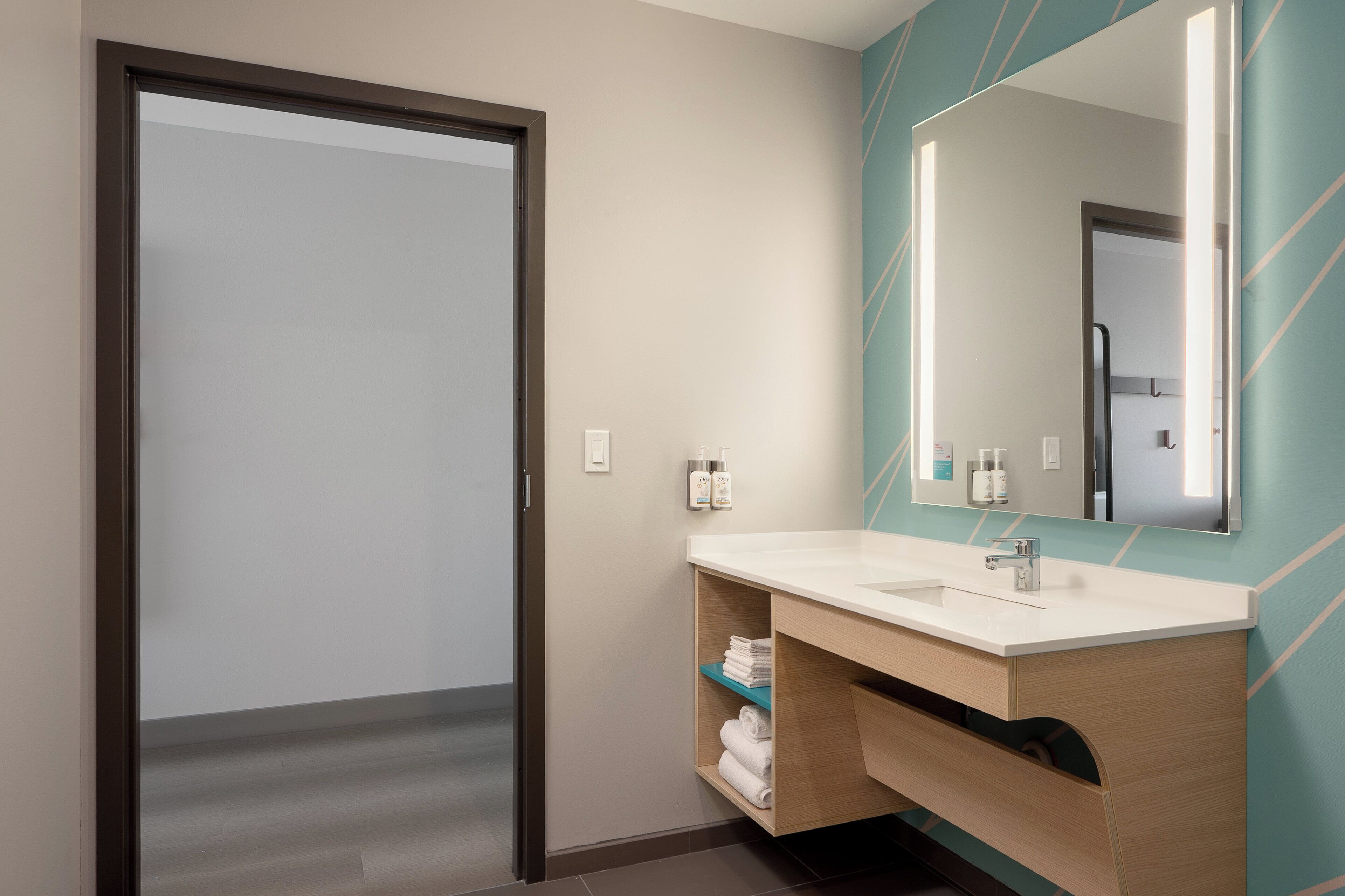 A modern bathroom with a large mirror, a sink, and a towel rack.