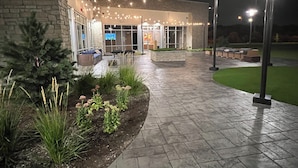 A building with a stone facade, outdoor seating, and string lights. - Holiday Inn Express & Suites Chicago Schaumburg by IHG (Schaumburg)