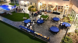 An outdoor patio area with tables and chairs, a pool, and a covered seating area. - Holiday Inn Express & Suites Chicago Schaumburg by IHG (Schaumburg)