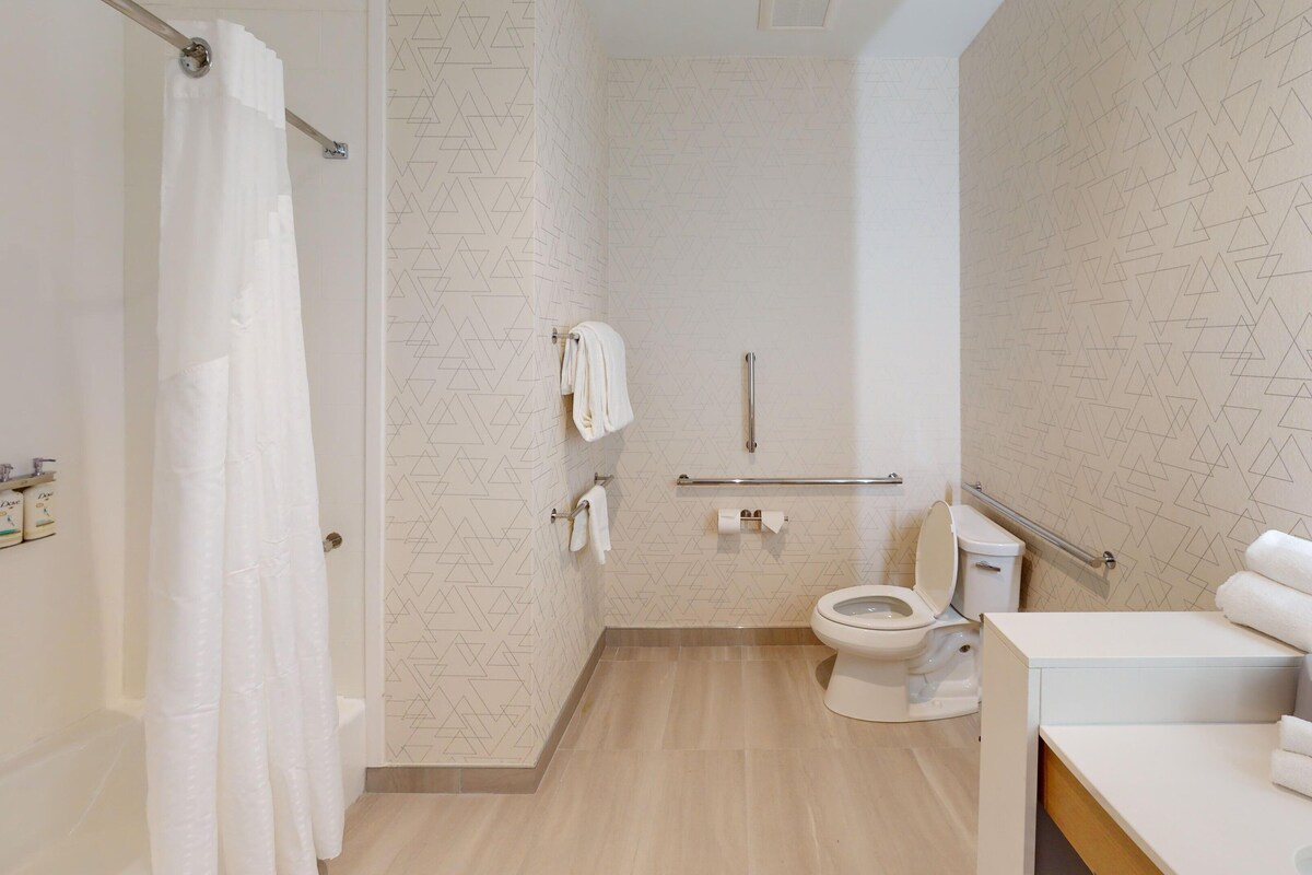 A modern bathroom with a shower, toilet, and sink.