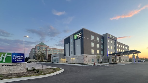 A Holiday Inn Express & Suites building with a modern design, a parking lot, and a gas station. - Holiday Inn Express & Suites Chicago Schaumburg by IHG (Schaumburg)