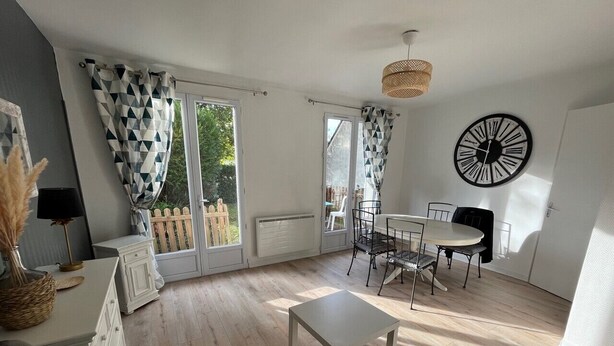 Un salon spacieux comprenant un canapé, une table basse, une table à manger avec des chaises et une grande fenêtre avec des rideaux.