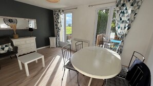 Un coin repas avec une table ronde et des chaises, un banc blanc, une commode et un miroir au mur.