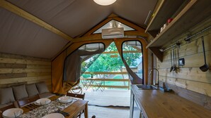Interior acogedor de una cabaña con comedor, cocina y un amplio ventanal con vistas a la vegetación.