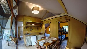Cocina compacta y bien iluminada con muebles de madera, un lavamanos y una zona de comedor con mesa preparada para cuatro.