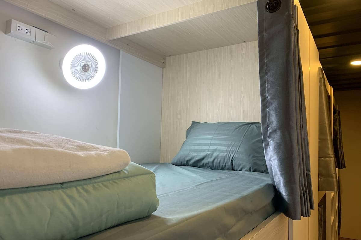 A bunk bed with a light green mattress and a white blanket.