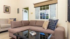 A living room with a beige sectional sofa, a glass coffee table, and a patterned rug. - Lot 40 Draxhall  (St. Ann's Bay)