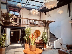 A spacious indoor area with a wooden staircase, a round wooden table with a vase of flowers, and hanging paper lanterns. - Hotel Quinta Bolivar  (Bogotá)